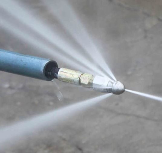A close-up of a high-pressure hose nozzle spraying water in multiple directions, perfect for tackling blocked drains Sydney.