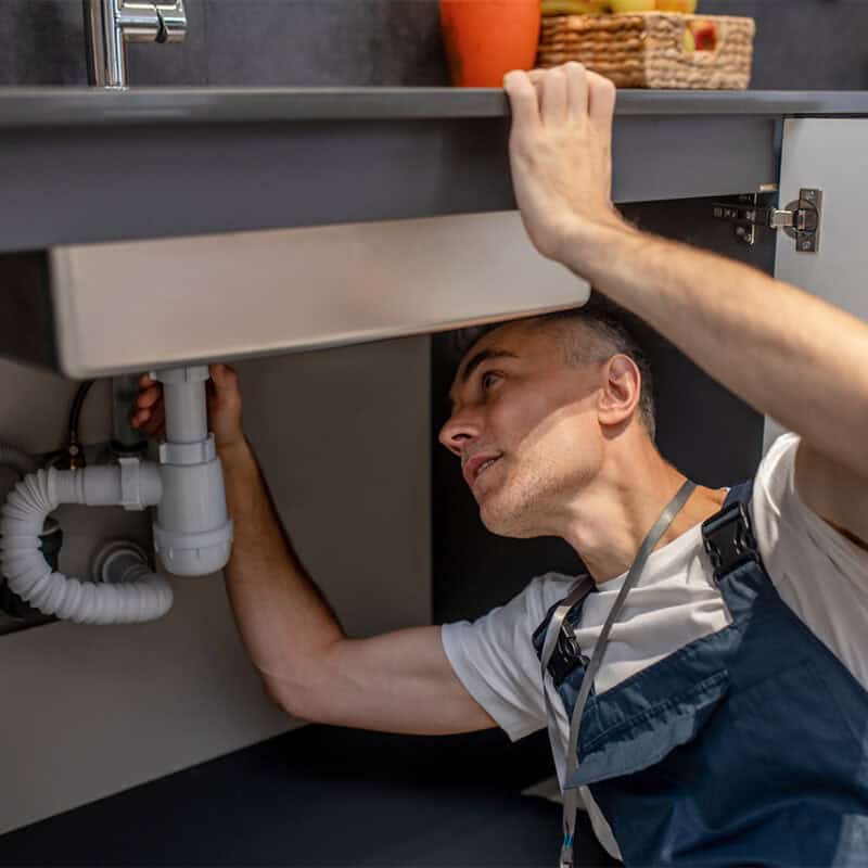 man-fixing-under-sink-pipes-kitchen