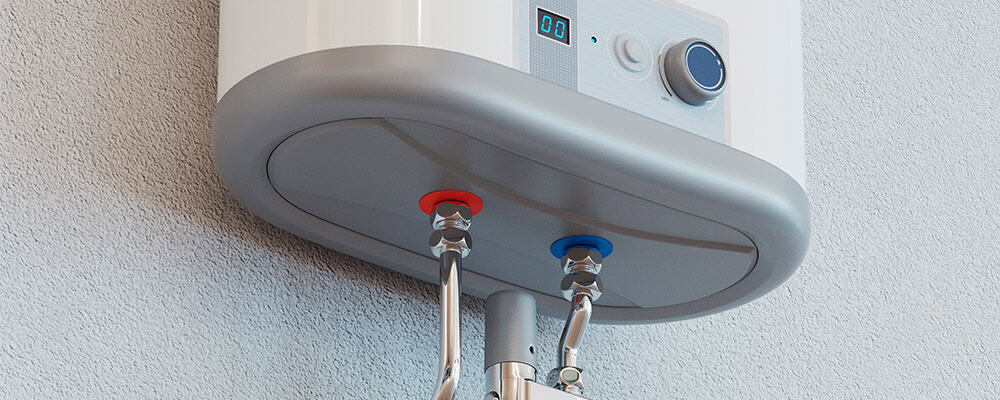 A close-up view of an installed tankless water heater attached to a wall. The heater has visible red and blue pipes for hot and cold water connections, seamlessly integrated with the water mains, a digital display, and a control knob.