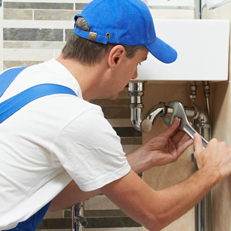 man fixing pipes under sink
